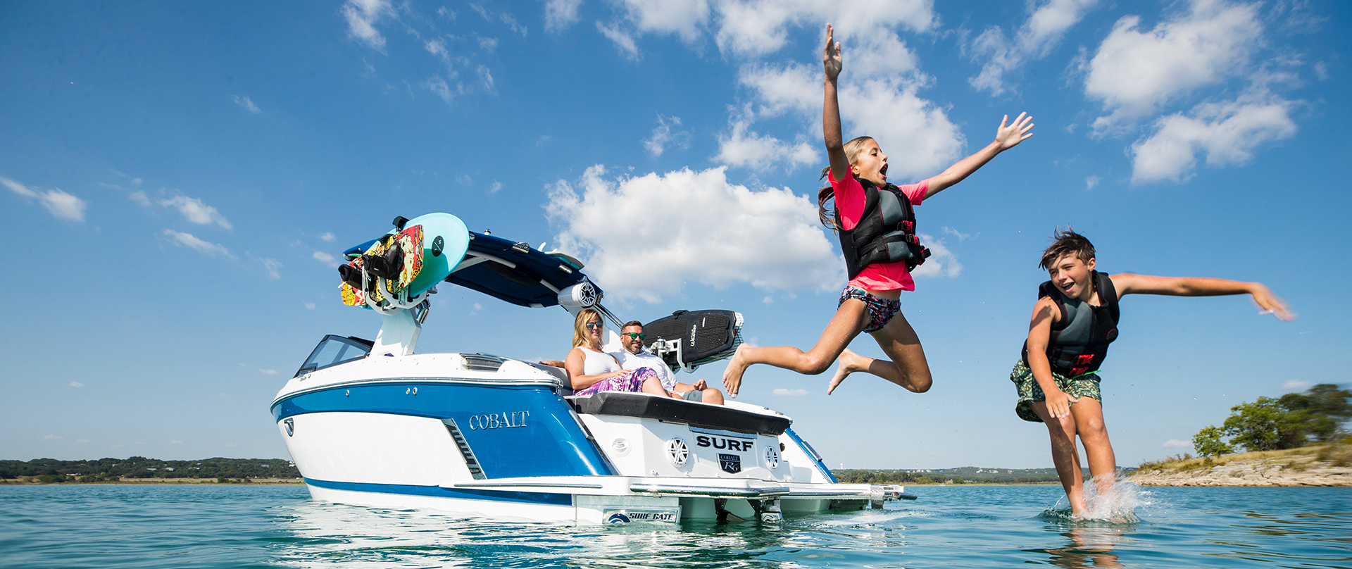 Kids jumping off of a Cobalt Boat